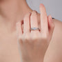 Silver ring with a diamond on a hand against a neutral background