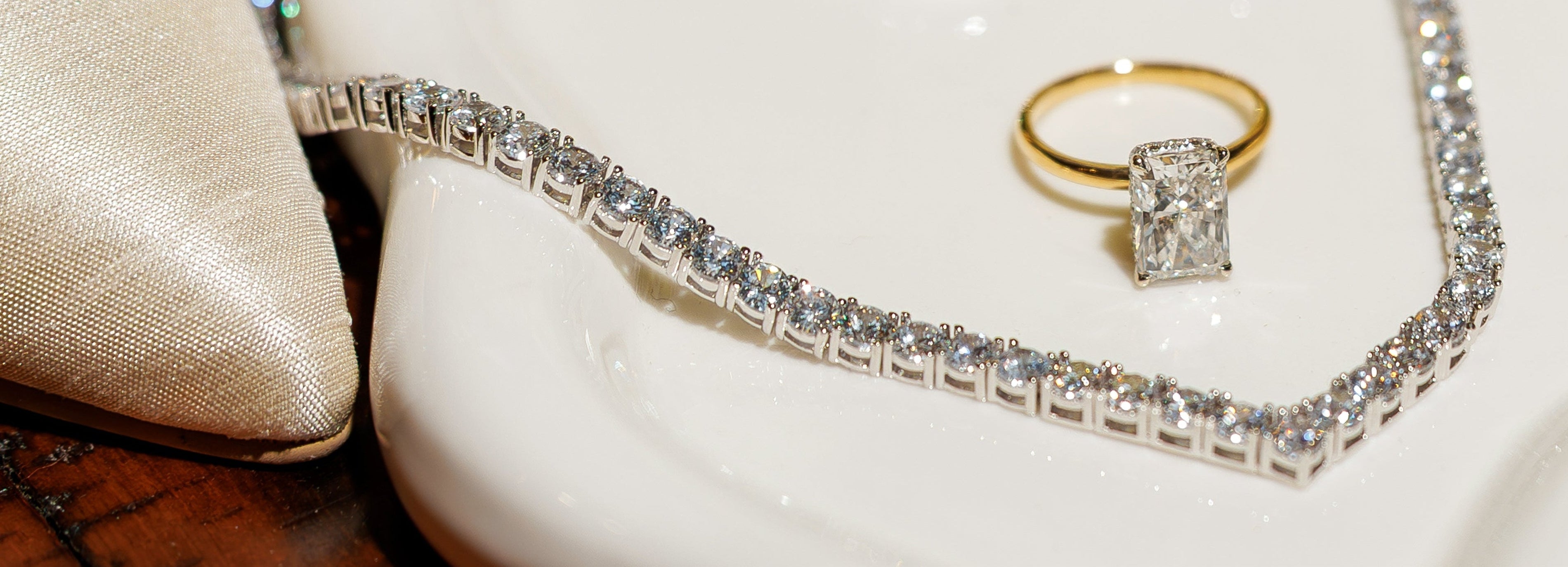 Jewelry including rings and a necklace on a white dish with a wooden surface.